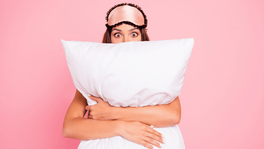 Women holding pillow, wearing an eye mask on her head looking ready to go to sleep.